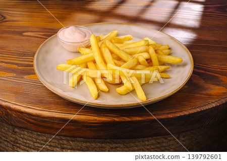Serving of French fries with dip on a round wooden table at a local eatery Serving of French fries with dip on a round wooden table at a local eatery 139792601