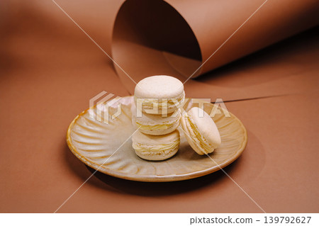 Delicious macarons stacked on a plate with brown background Delicious macarons stacked on a plate with brown background 139792627