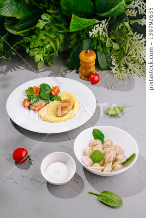 Healthy meal with dumplings, salad, and sauce on a gray table Healthy meal with dumplings, salad, and sauce on a gray table 139792635