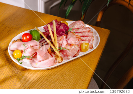 Platter of assorted meats and vegetables on a wooden table displayed in a home Platter of assorted meats and vegetables on a wooden table displayed in a home 139792683