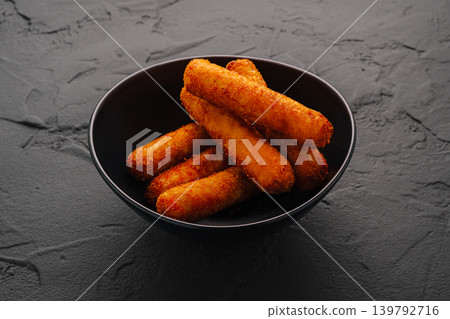 Crunchy fried snacks served in a black bowl on a dark surface Crunchy fried snacks served in a black bowl on a dark surface 139792716