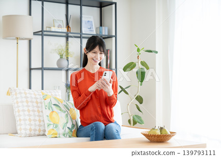在客廳裡使用智能手機的中年婦女 在客廳裡使用智能手機的中年婦女 139793111