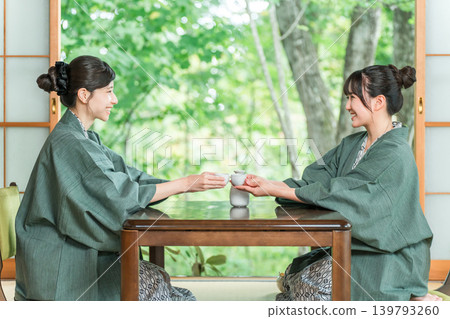 Women and friends drinking sake in yukata on the veranda of a Japanese-style room in a Japanese inn Women and friends drinking sake in yukata on the veranda of a Japanese-style room in a Japanese inn 139793260