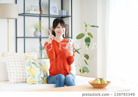 在客廳裡使用智能手機的中年婦女 在客廳裡使用智能手機的中年婦女 139793349