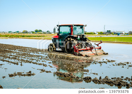 A film-like scene of rice paddy plowing and a tractor. A film-like scene of rice paddy plowing and a tractor. 139793876