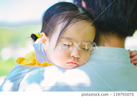 A little girl fell asleep while being held by her dad. A little girl fell asleep while being held by her dad. 139793878