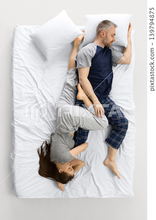 Couple sleeping in upside down pose on white bed from overhead view 139794875