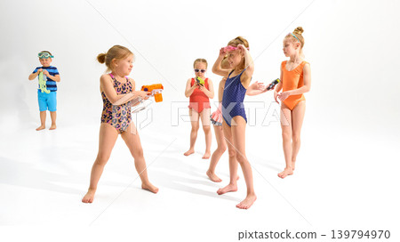 Kids playing with toy water guns and goggles on white studio background. Kids playing with toy water guns and goggles on white studio background. 139794970