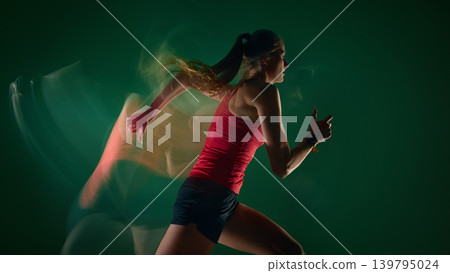 Female runner sprinting with motion blur trail on green studio background Female runner sprinting with motion blur trail on green studio background 139795024