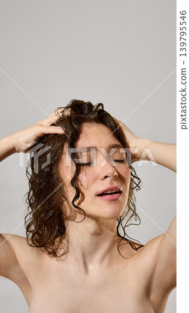 Woman enjoying scalp massage on wet curly hair in clean beauty portrait. Woman enjoying scalp massage on wet curly hair in clean beauty portrait. 139795546