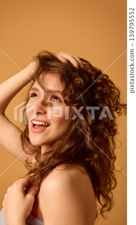 Woman with wet curly hair using scalp massage brush on clean studio background Woman with wet curly hair using scalp massage brush on clean studio background 139795552
