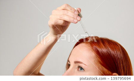 Close up of hair serum drops on glossy red hair roots. Close up of hair serum drops on glossy red hair roots. 139795694