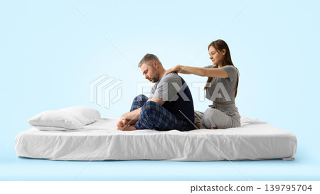 Woman massaging man shoulders on white bed from side view on blue background. Woman massaging man shoulders on white bed from side view on blue background. 139795704