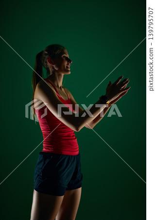 Female runner clapping hands after workout on dramatic green studio background Female runner clapping hands after workout on dramatic green studio background 139795707