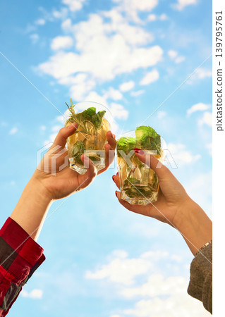 Friends clinking mint cocktails under bright summer sky Friends clinking mint cocktails under bright summer sky 139795761