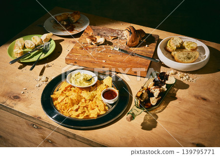Messy snack table with nachos, dips, bread and pastry after casual food tasting. Messy snack table with nachos, dips, bread and pastry after casual food tasting. 139795771