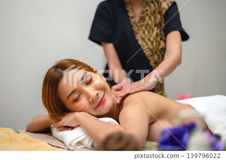 Soft light bathes a relaxed woman receiving massage Soft light bathes a relaxed woman receiving massage 139796022