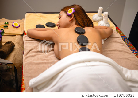 Woman relaxes with hot stones on her back Woman relaxes with hot stones on her back 139796025