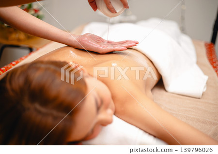 Woman relaxes with oil being poured gently over her skin 139796026