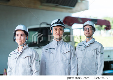 建築工人戴著安全帽,旁邊還有一輛卡車。 建築工人戴著安全帽,旁邊還有一輛卡車。 139796072