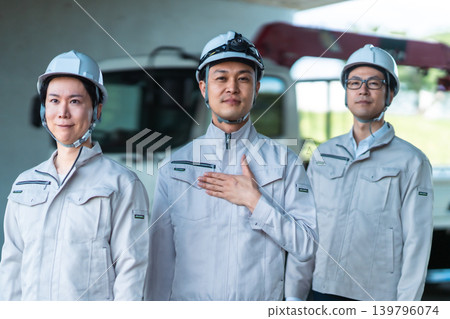 建築工人戴著安全帽,旁邊還有一輛卡車。 建築工人戴著安全帽,旁邊還有一輛卡車。 139796074