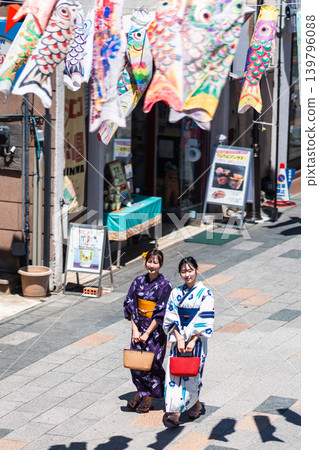 A woman in a yukata (summer kimono) sightseeing in Koedo Kawagoe, with a panoramic view of the traditional storehouse-style townscape. A woman in a yukata (summer kimono) sightseeing in Koedo Kawagoe, with a panoramic view of the traditional storehouse-style townscape. 139796088