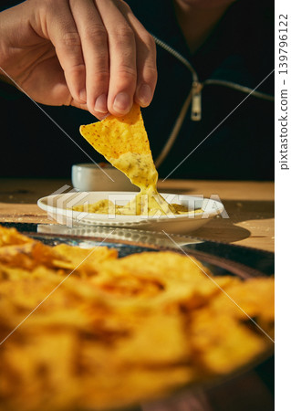 Tortilla chip dipped into creamy cheese sauce on plate in appetizing closeup 139796122