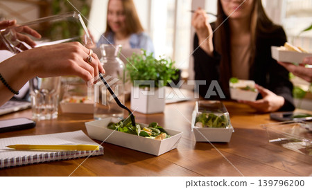 Office workers eating salads together during lunch break. Office workers eating salads together during lunch break. 139796200