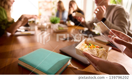 Office worker opening delivered lunch box at wooden conference table. Office worker opening delivered lunch box at wooden conference table. 139796202
