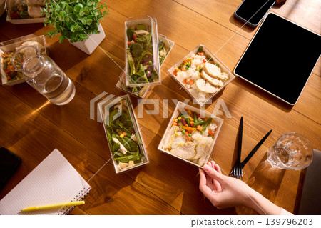 Delivered office lunches with chicken rice and salads on wooden meeting table. Delivered office lunches with chicken rice and salads on wooden meeting table. 139796203