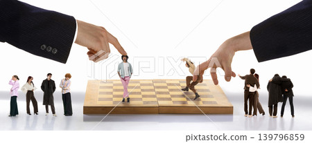 Giant hands moving miniature people on chess board with spectators. 139796859