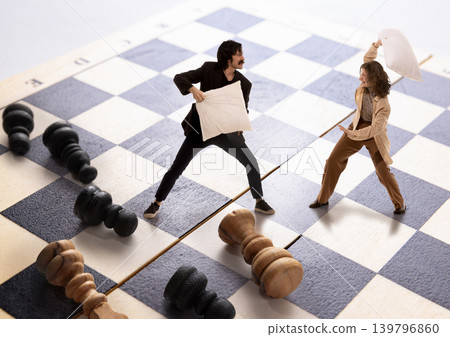 Miniature coworkers having pillow fight on chess board battlefield. Miniature coworkers having pillow fight on chess board battlefield. 139796860