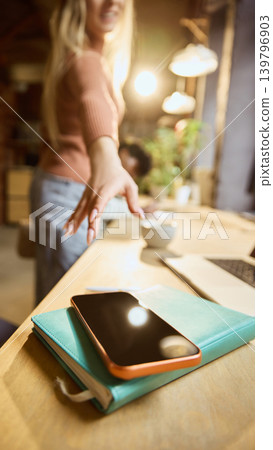 Close up of woman reaching for phone at workspace. Close up of woman reaching for phone at workspace. 139796903