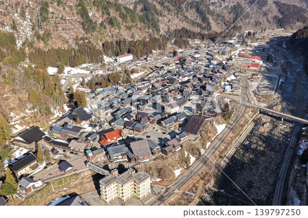 一張冬季空拍照片,從傾斜角度拍攝,展現了石川縣的一個山村和鐵路線。 一張冬季空拍照片,從傾斜角度拍攝,展現了石川縣的一個山村和鐵路線。 139797250