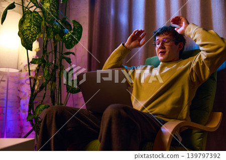 Young man reacting to online order confirmation on laptop at home ecommerce success moment 139797392