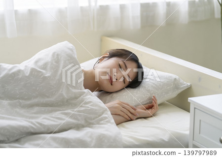 一位年輕女子睡在床上；她熟睡的臉 139797989