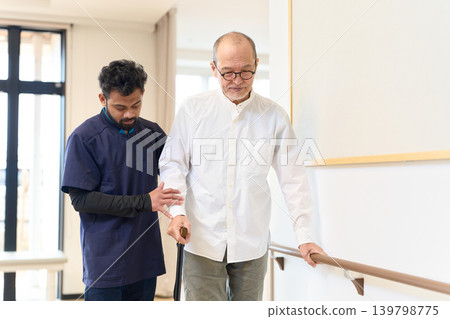 Seniors and foreign caregivers practice walking using handrails and canes. Seniors and foreign caregivers practice walking using handrails and canes. 139798775