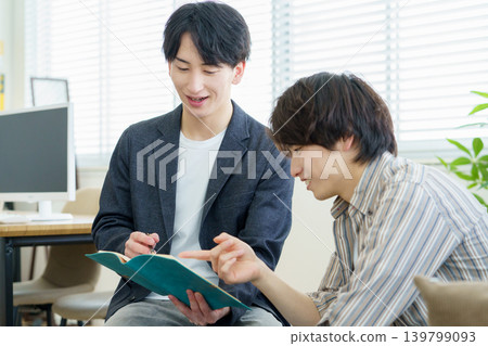 一位年輕的日本醫生在諮詢過程中一邊聽客戶傾訴一邊做筆記。 一位年輕的日本醫生在諮詢過程中一邊聽客戶傾訴一邊做筆記。 139799093