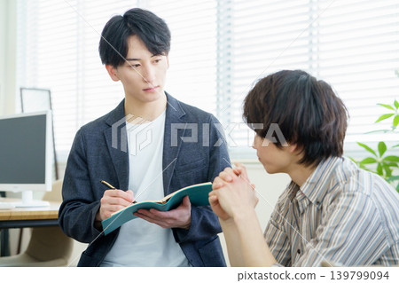 一位年輕的日本醫生在諮詢過程中一邊聽客戶傾訴一邊做筆記。 139799094