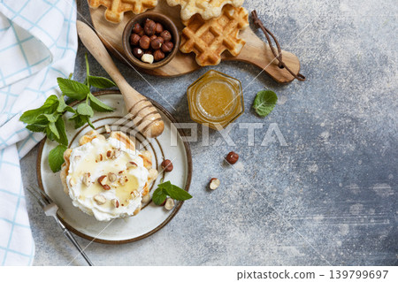 Belgian waffles with ricotta cheese, honey and hazelnuts for breakfast on a stone background. Sweet breakfast gluten free. Summer homemade recipe. View from above. Copy space. 139799697