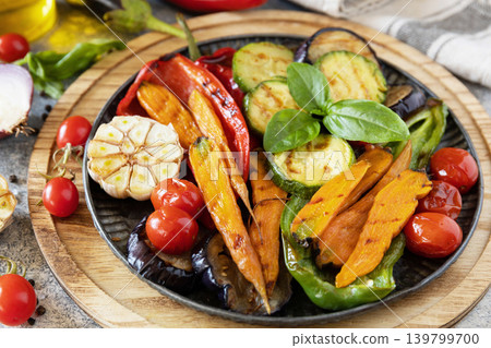 Grilled vegetables close-up: red and yellow paprika, garlic, zucchini, eggplants, carrots on a stone tabletop. 139799700