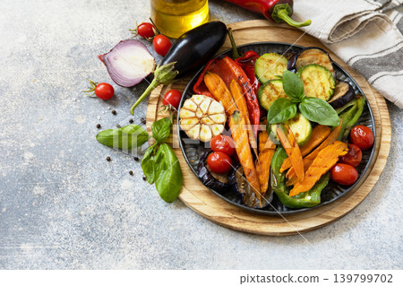 Grilled vegetables: red and yellow paprika, garlic, zucchini, eggplants, carrots on a stone tabletop. Summer homemade recipe. Copy space. Grilled vegetables: red and yellow paprika, garlic, zucchini, eggplants, carrots on a stone tabletop. Summer homemade recipe. Copy space. 139799702