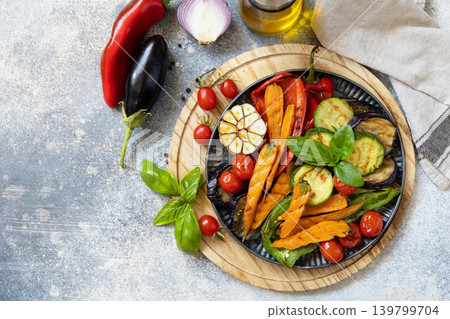 Grilled vegetables: red and yellow paprika, garlic, zucchini, eggplants, carrots on a stone tabletop. Summer homemade recipe. View from above. Grilled vegetables: red and yellow paprika, garlic, zucchini, eggplants, carrots on a stone tabletop. Summer homemade recipe. View from above. 139799704
