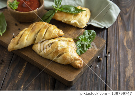 Mini savory meat pies from flaky dough on a wooden board over wooden background. Copy space. Mini savory meat pies from flaky dough on a wooden board over wooden background. Copy space. 139799747