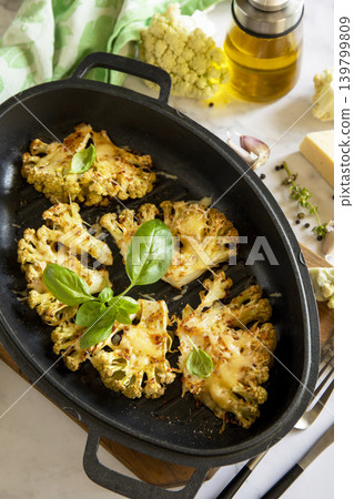Baked cauliflower keto steaks with cheese on a stone table. Vegetarian cauliflower parmesan. Healthy eating, plant-based meat substitute concept. Baked cauliflower keto steaks with cheese on a stone table. Vegetarian cauliflower parmesan. Healthy eating, plant-based meat substitute concept. 139799809
