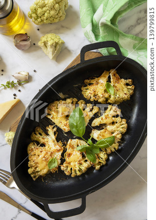Baked cauliflower keto steaks with cheese on a stone table. Vegetarian cauliflower parmesan. Healthy eating, plant-based meat substitute concept. View from above. 139799815