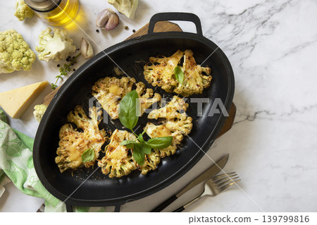 Baked cauliflower keto steaks with cheese on a stone table. Vegetarian cauliflower parmesan. Healthy eating, plant-based meat substitute concept. View from above. Copy space. 139799816