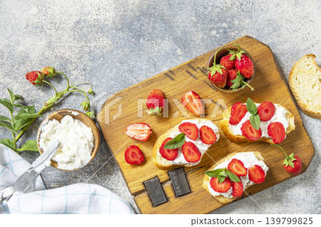 Bruschetta with ricotta and strawberry on a stone tabletop. Berries toast summer breakfast, healthy food. View from above. 139799825