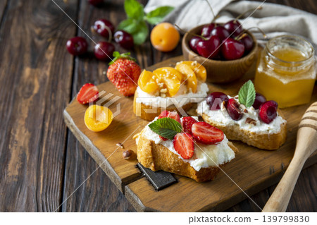 Assorted bruschetta with ricotta, honey, cherries, apricot and strawberry on a rustic table. Berries toast summer breakfast, healthy food. Assorted bruschetta with ricotta, honey, cherries, apricot and strawberry on a rustic table. Berries toast summer breakfast, healthy food. 139799830
