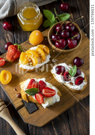 Assorted bruschetta with ricotta, honey, cherries, apricot and strawberry on a rustic table. Berries toast summer breakfast, healthy food. Assorted bruschetta with ricotta, honey, cherries, apricot and strawberry on a rustic table. Berries toast summer breakfast, healthy food. 139799831